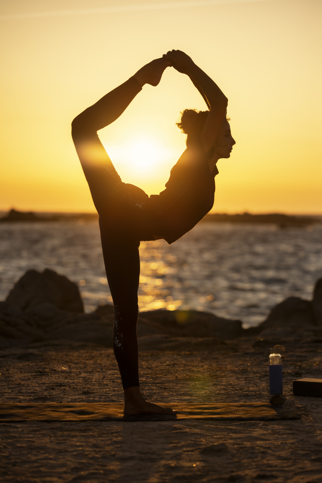 Ines Lamour doing a King Dancer Pose in front of a sea sunset